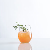 passion fruit non alcoholic spritz in glass with simple rosemary garnish
